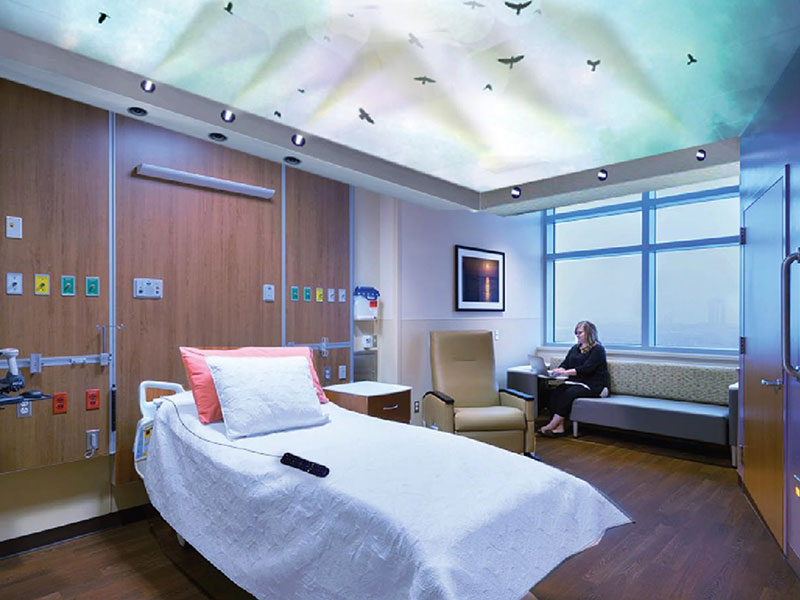 A woman sits in a hospital room with an empty bed.